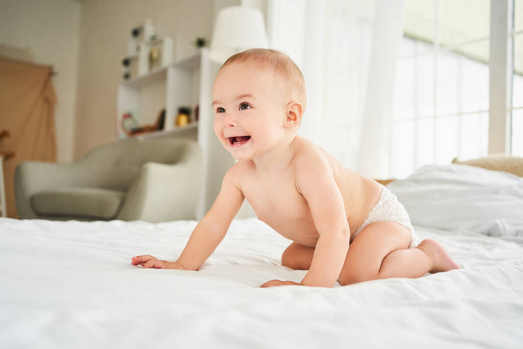 Cute little small child caucasian infant toddler newborn smiling with baby milk teeth lying on the comfortable bed. Teething concept, childcare and parenthood. Copy space. - Photo, Image