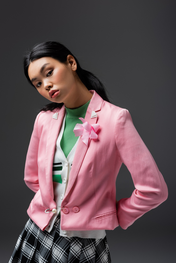 modny młody Azji model w różowy kurtka patrząc na kamery odizolowane na szary  - Zdjęcie, obraz