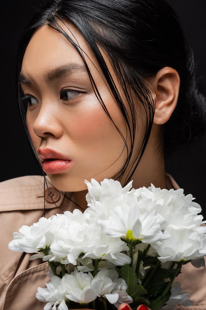 黒に孤立した白い菊を持つ若いアジアの女性の肖像画  - 写真・画像
