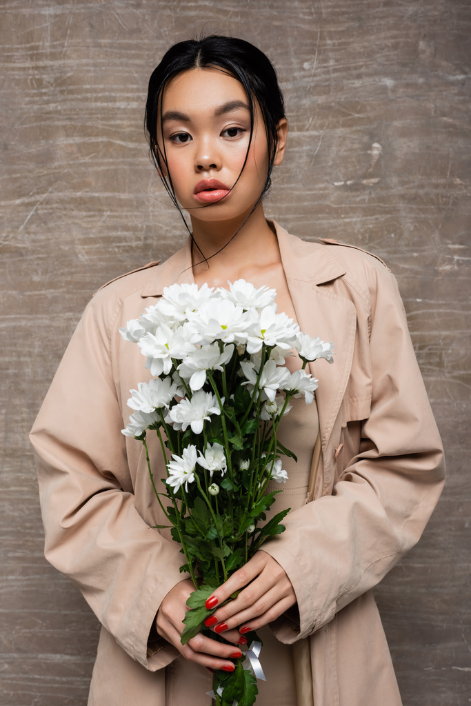 Porträt einer asiatischen Frau mit Chrysanthemen auf abstraktem braunem Hintergrund  - Foto, Bild