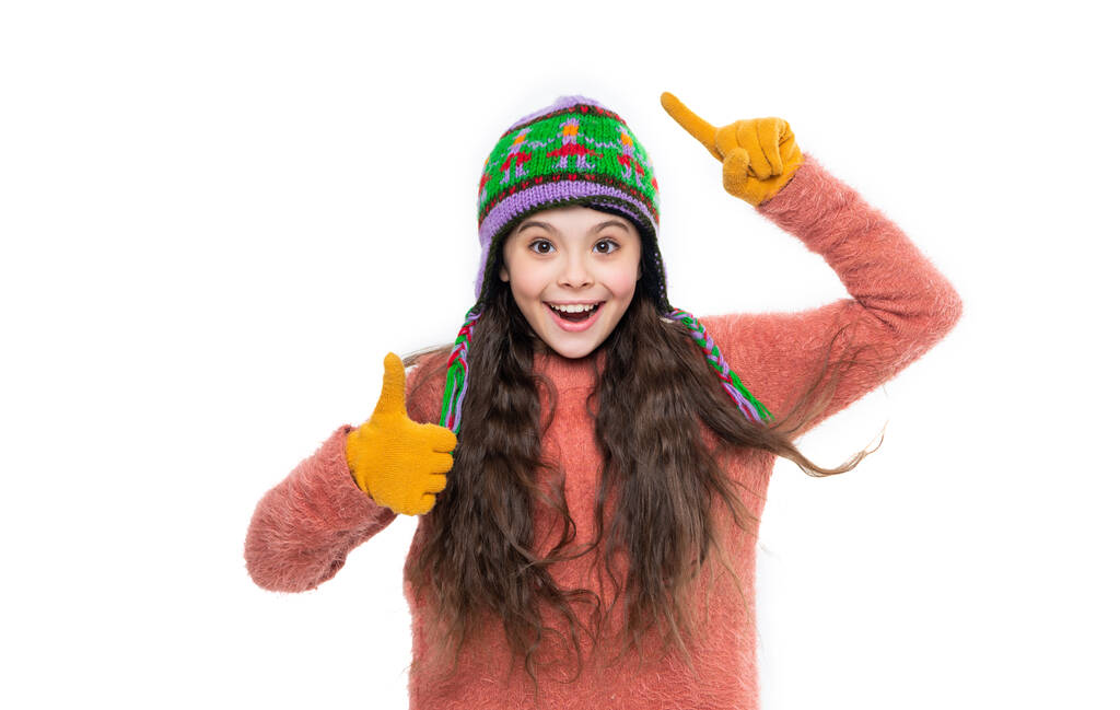 teen girl in winter hat show thumb up isolated on white background. teen girl wear sweater and winter hat in studio. winter fashion for teen girl. winter knitwear. teen girl model in earflap hat. - Photo, Image