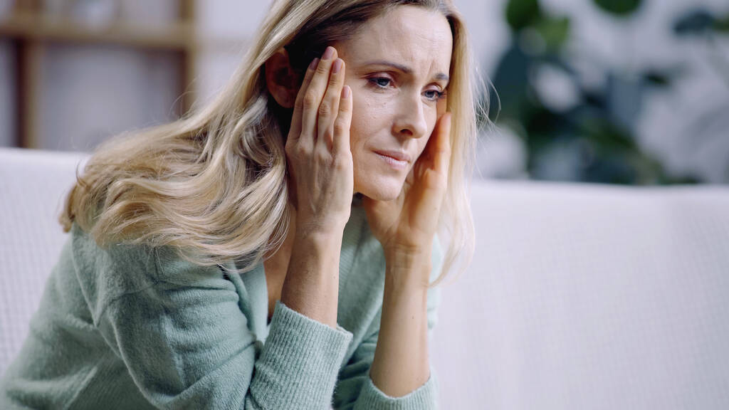 donna triste che ha l'emicrania mentre tocca la testa in soggiorno - Foto, immagini