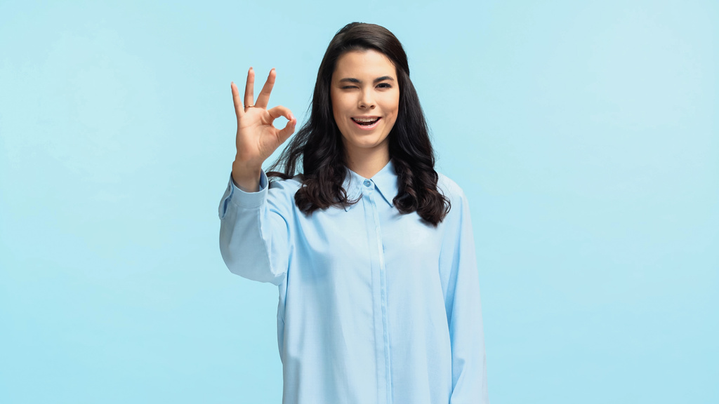happy young woman in shirt looking at camera while showing ok isolated on blue - Photo, Image