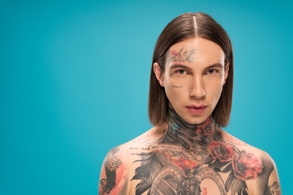 bez košile mladý muž s tetováním při pohledu na kameru izolované na modré  - Fotografie, Obrázek