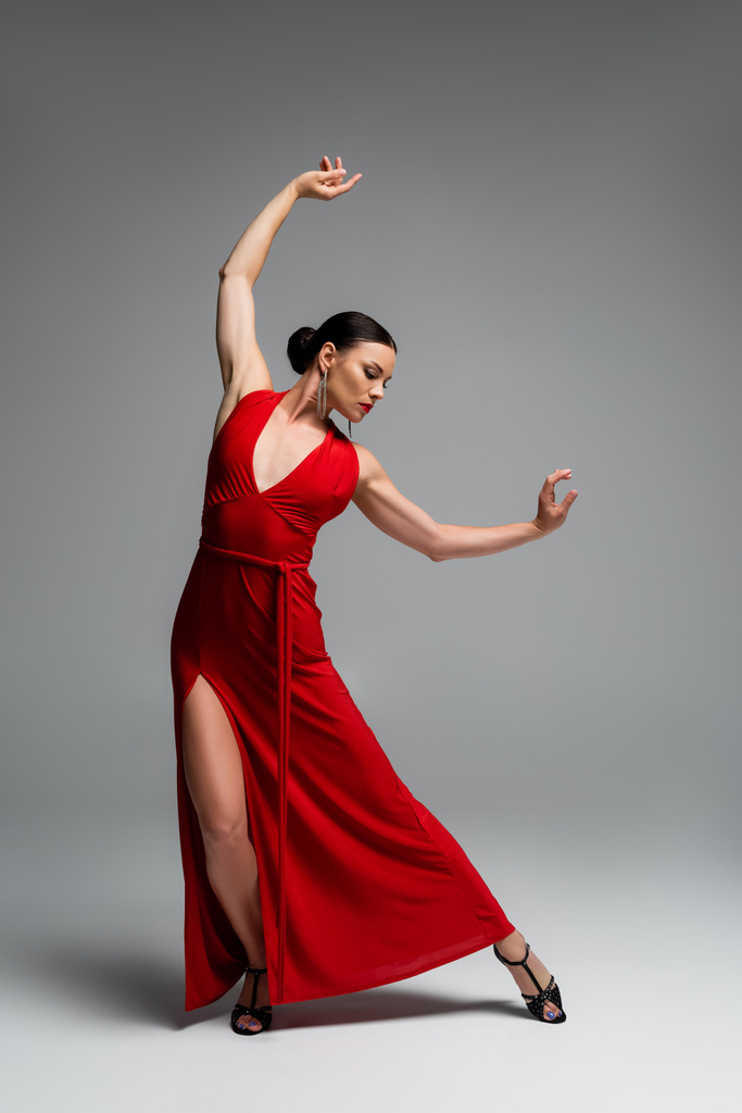 Nainen punaisessa mekossa ja korkokengät tanssia harmaalla taustalla - Valokuva, kuva