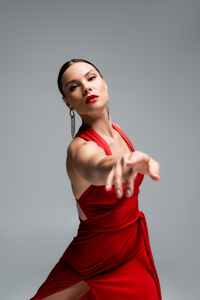 Tancerka w czerwonej sukience wskazująca palcem na kamerę odizolowana na szaro  - Zdjęcie, obraz