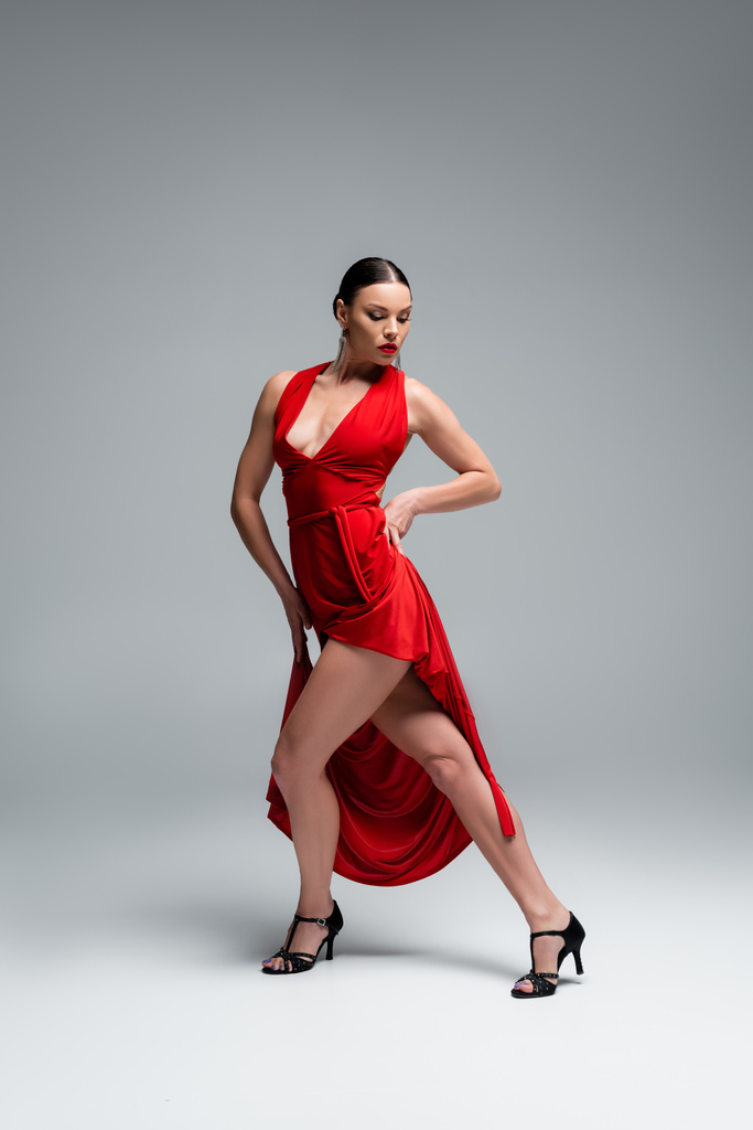 Профессиональная танцовщица на каблуках, исполняющая хореографию танго на сером фоне - Фото, изображение