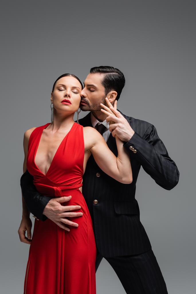Vášnivý muž v obleku tango s elegantním partnerem izolované na šedé  - Fotografie, Obrázek