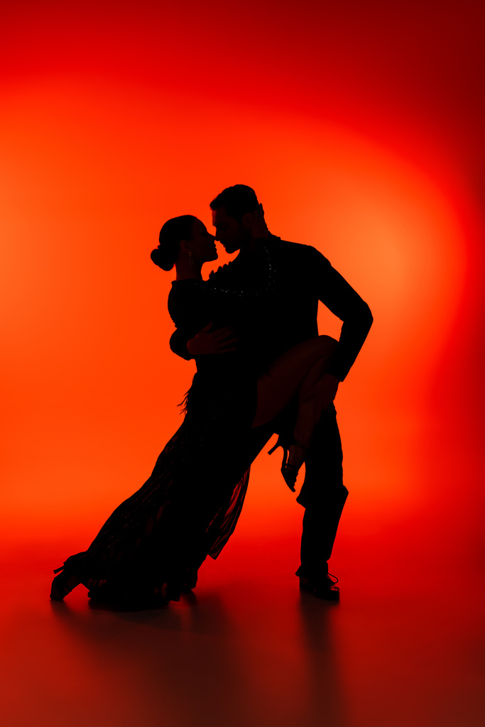 Seitenansicht der Silhouette eines tanzenden Paares Tango auf rotem Hintergrund  - Foto, Bild