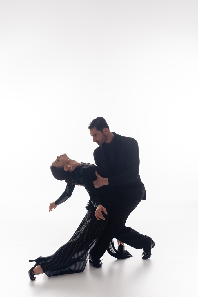 Paar in pak en jurk uitvoeren tango op witte achtergrond  - Foto, afbeelding
