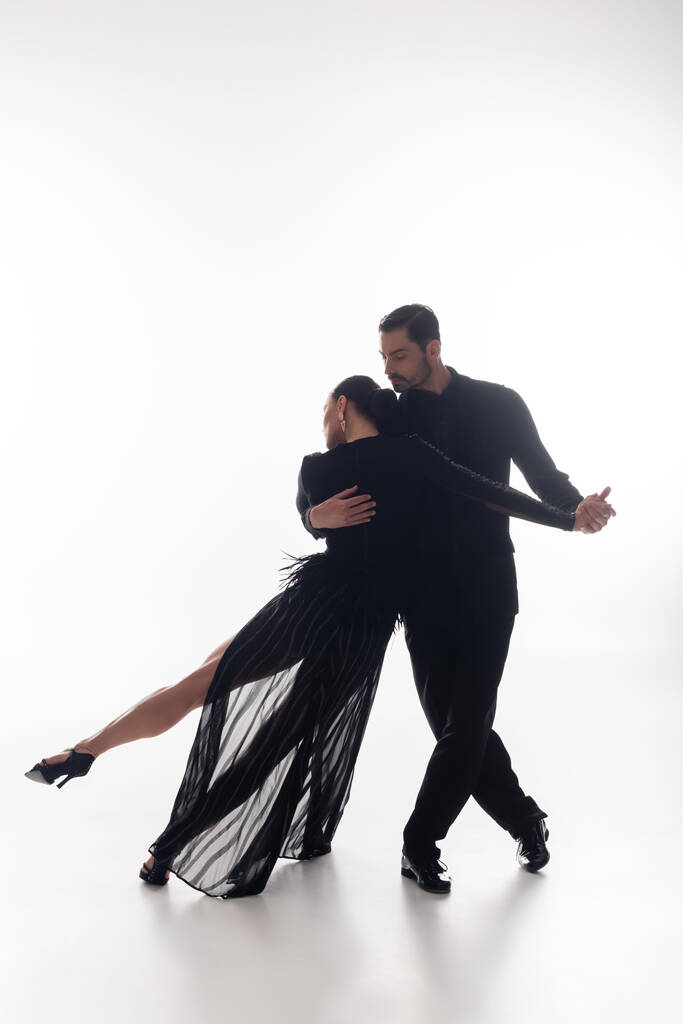 Man in suit performing tango with elegant woman on white background  - Photo, Image