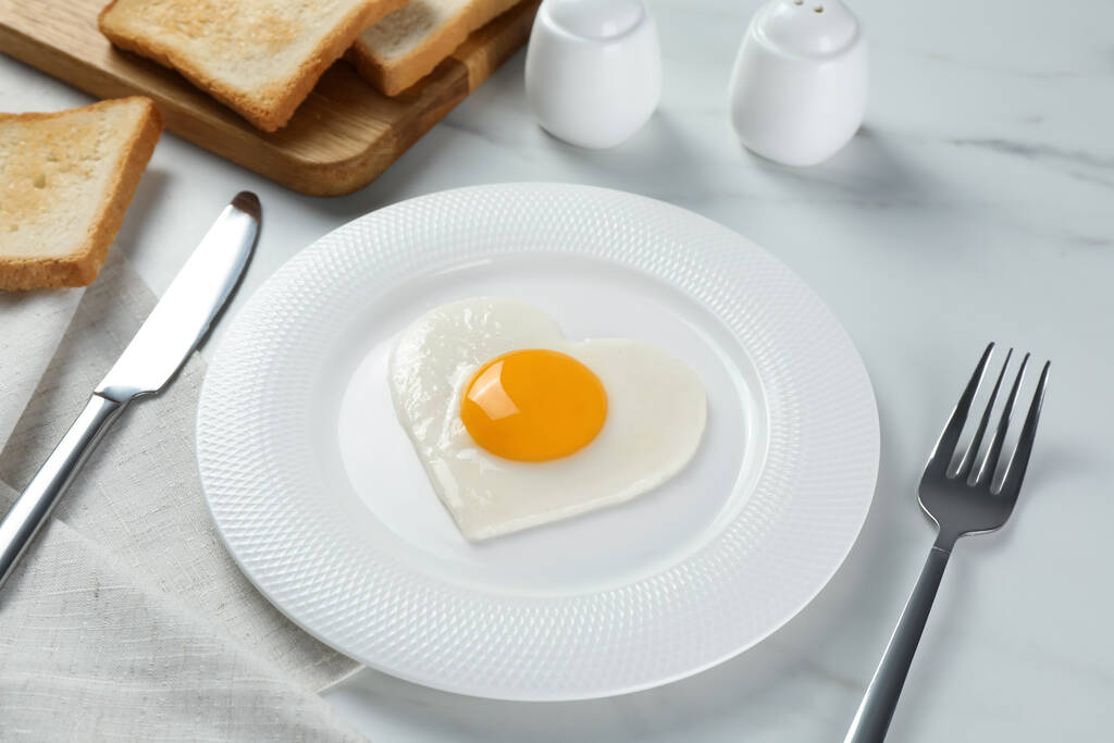 Romantic breakfast with heart shaped fried egg served on white marble table - Photo, Image