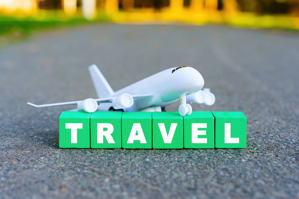 Aircraft model and word TRAVEL arranged from wooden alphabet blocks. - Photo, Image