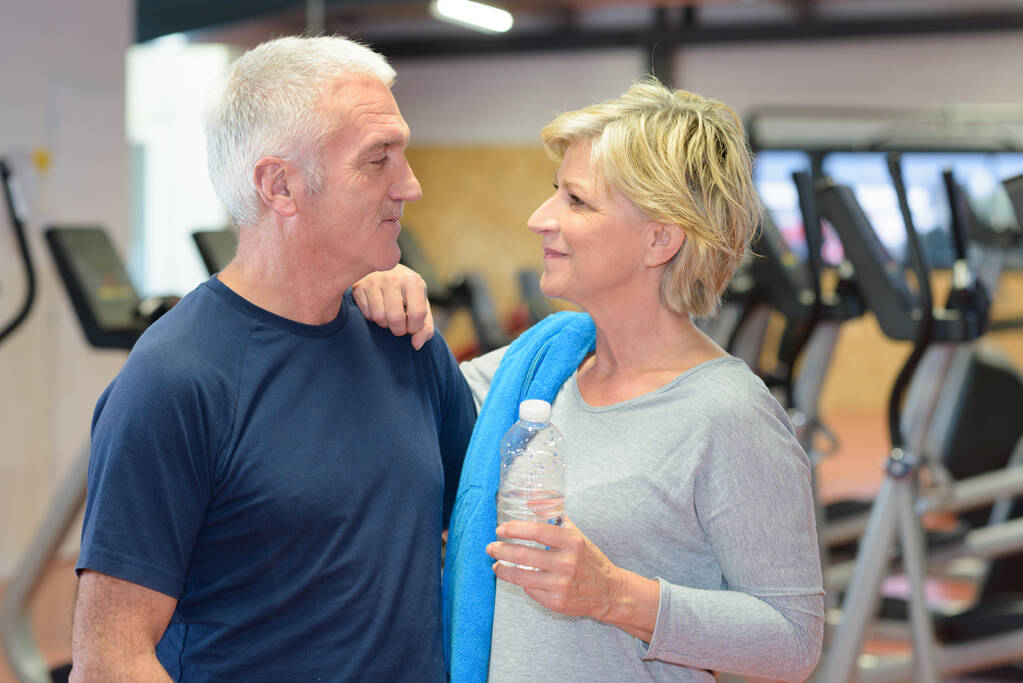 άνδρας και γυναίκα ποζάρουν σε ένα γυμναστήριο και χαμογελούν - Φωτογραφία, εικόνα