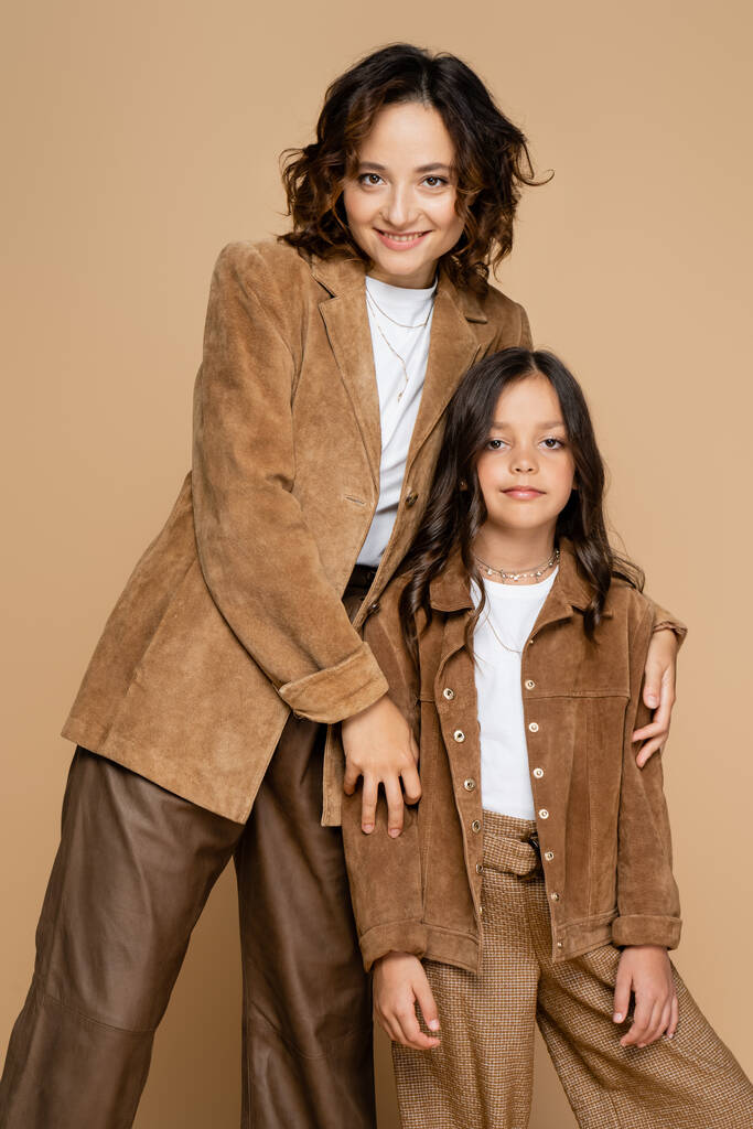 mère et fille en tenue d'automne élégante souriant à la caméra isolée sur beige - Photo, image