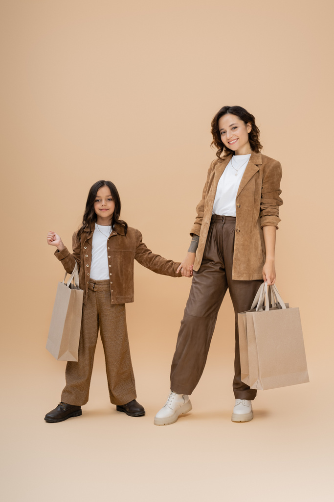 幸せなお母さんと娘で流行の秋服保持手とショッピングバッグでベージュ  - 写真・画像