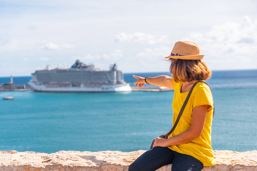 Una giovane donna che indica la nave da crociera che è arrivata sull'isola di Ibiza dal muro del castello, Isole Baleari, Eivissa - Foto, immagini