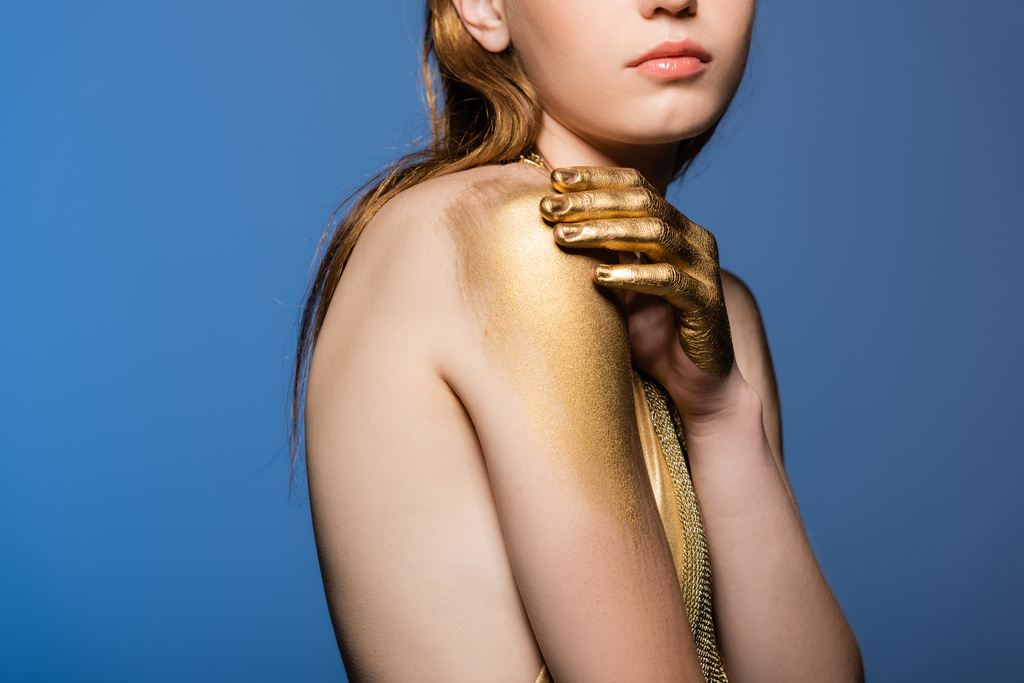 Vista ritagliata di giovane donna con tintura dorata a mano toccando spalla isolata su blu  - Foto, immagini