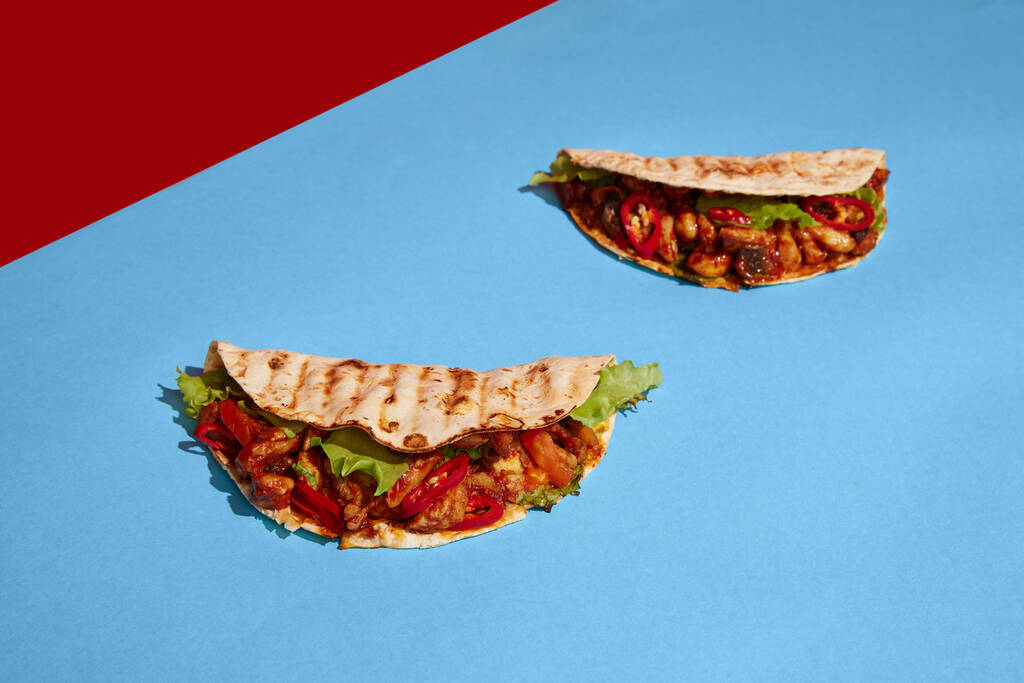 Mexická kuchyně. Chutné a šťavnaté tacos na červenomodrém pozadí. Ročník, retro styl. Jídlo pop art fotografie. Barevný minimalismus. Kopírovat prostor pro inzerci, text - Fotografie, Obrázek