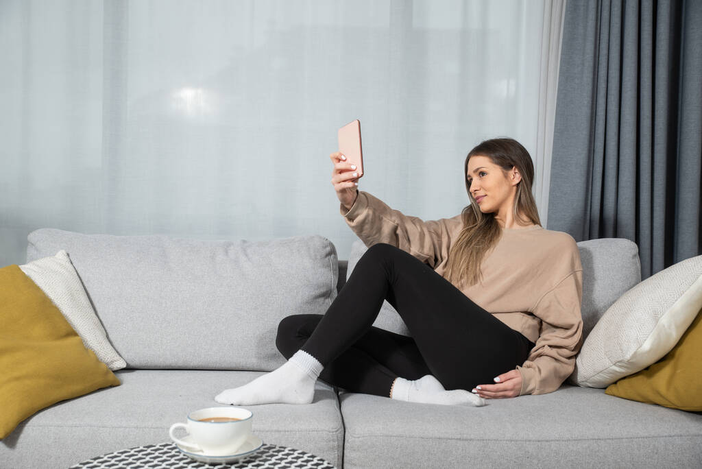 glückliche junge Anruferin telefoniert zu Hause, fröhliches Teenie-Mädchen genießt angenehme mobile Unterhaltung, lächelnde Millennial-Frau mit Handy telefoniert im Wohnzimmer - Foto, Bild
