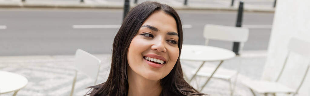 Πορτρέτο της νεαρής μελαχρινής γυναίκας χαμογελώντας σε αστικό δρόμο, πανό  - Φωτογραφία, εικόνα