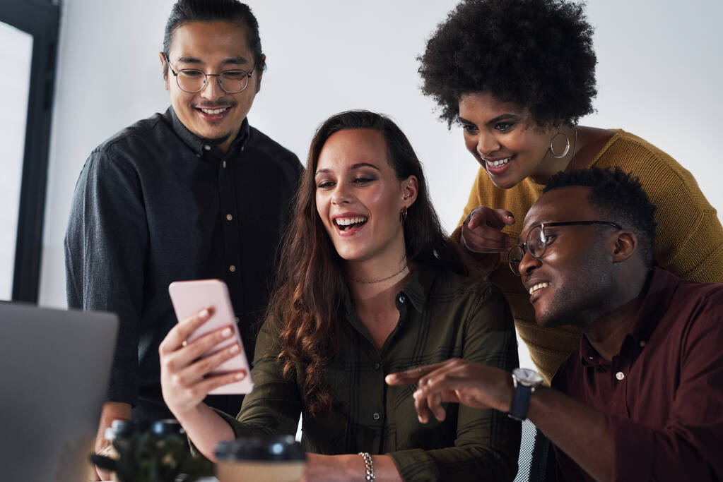 ¿Dónde estaríamos sin tecnología? un grupo diverso de empresarios que miran un teléfono celular juntos en la oficina - Foto, imagen