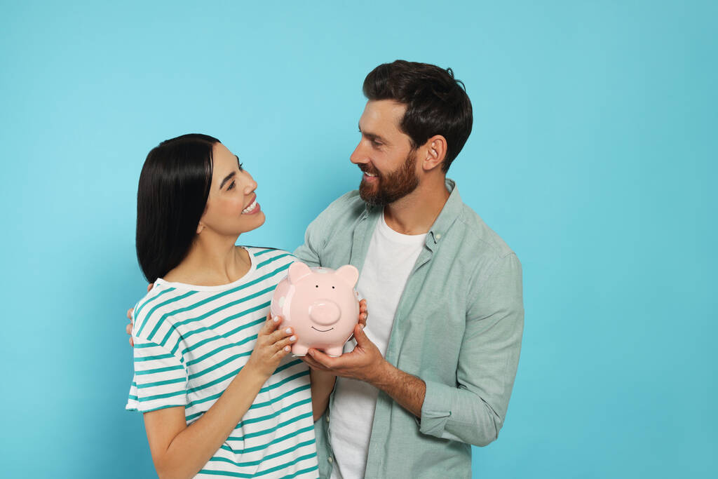 Onnellinen pari keraaminen säästöpossu vaaleansinisellä taustalla - Valokuva, kuva