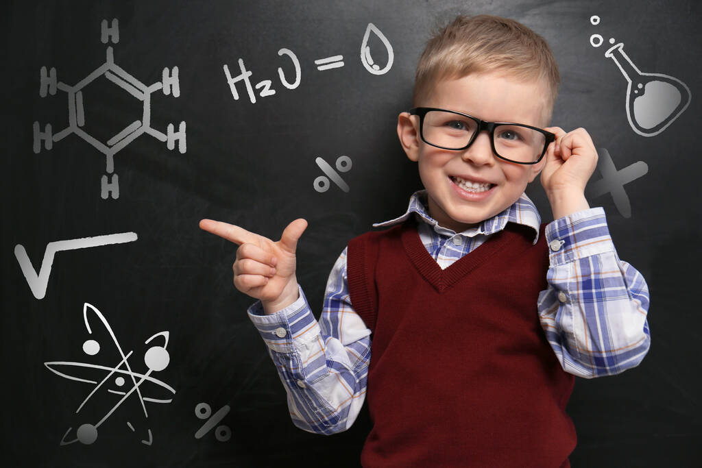 Милый маленький ребенок в очках возле доски с химическими формулами - Фото, изображение