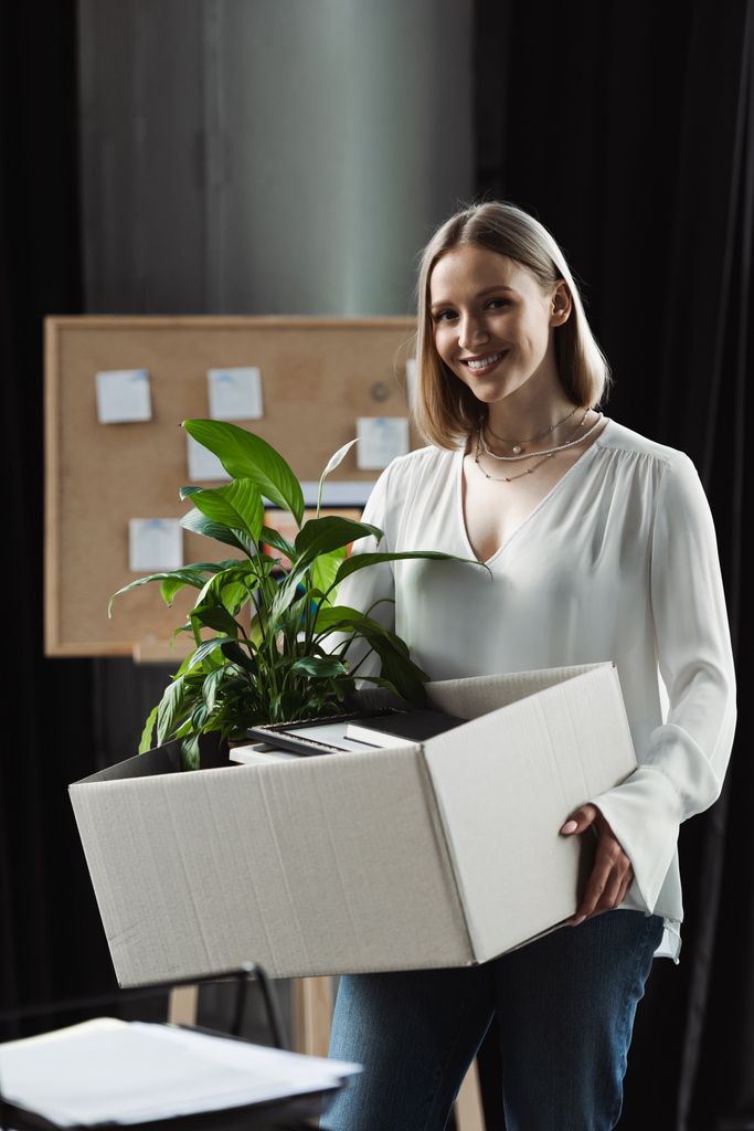 Positivo novo trabalhador segurando caixa de papelão com coisas no escritório  - Foto, Imagem