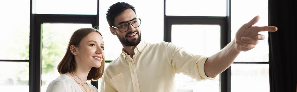 Χαρούμενος επιχειρηματίας που δείχνει με το δάχτυλο κοντά οικότροφος στο γραφείο, πανό  - Φωτογραφία, εικόνα