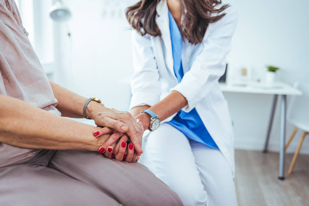 jeune femme médecin tenant la main de sa patiente âgée à la clinique - Photo, image