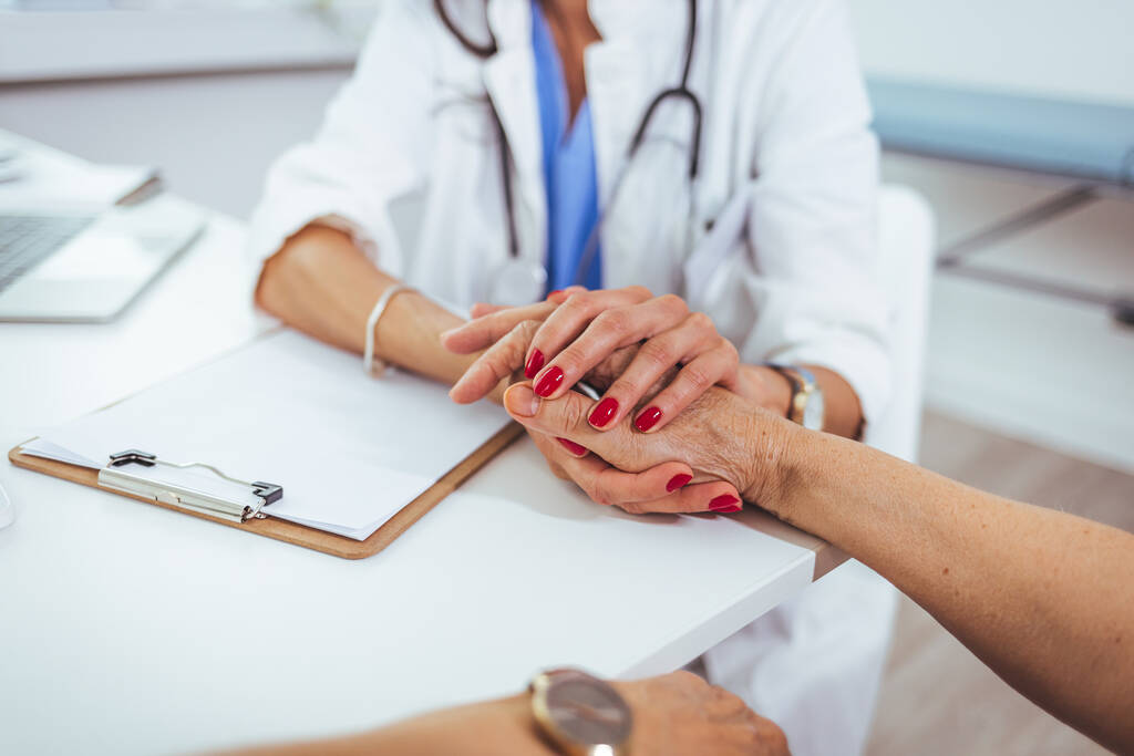 Жінка-лікар тримає руки пацієнта на зустрічі з жінками як концепція охорони здоров'я медичної допомоги експрес-підтримка довіри співпереживання щодо викидня, допомога в лікуванні ракових захворювань, крупним планом
 - Фото, зображення