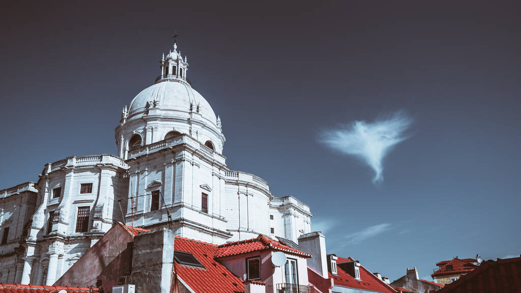 Widok na Kościół Santa Engracia lub inną nazwę Panteon Narodowy jasny zimny dzień, z głębokim błękitnym niebem i pojedynczą chmurą w postaci anioła obok kopuły i czerwonych dachów domów - Zdjęcie, obraz