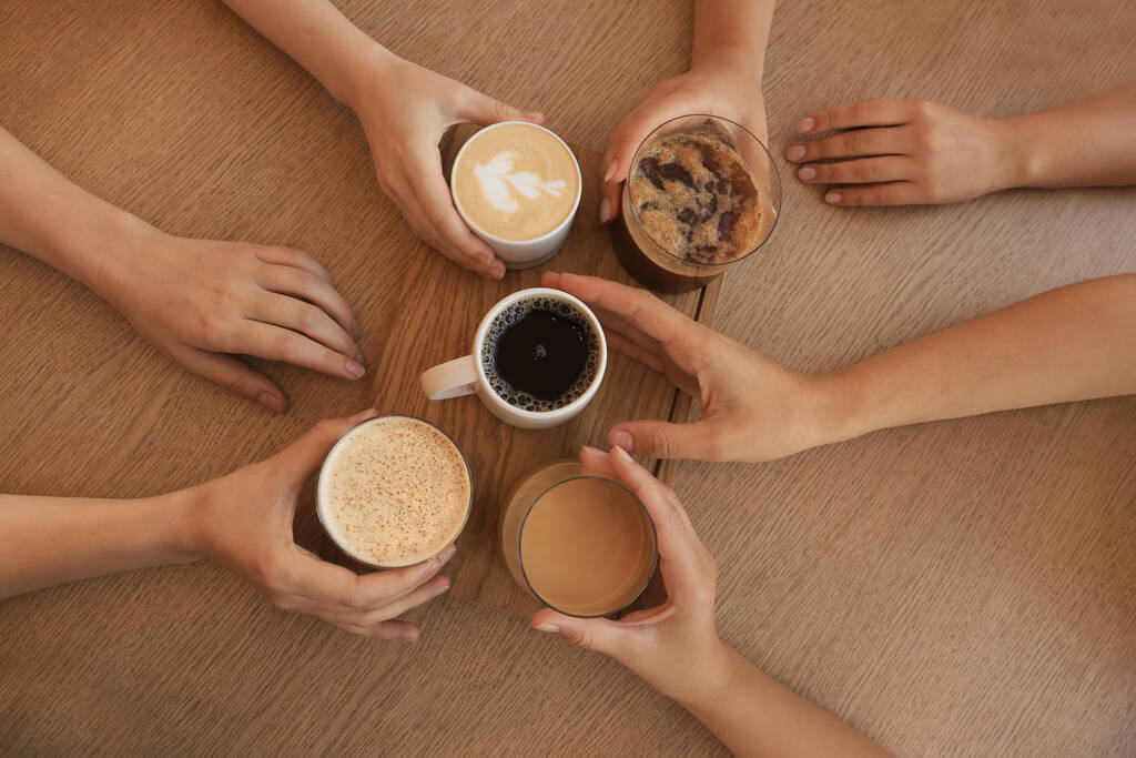 Amici che bevono caffè al tavolo di legno in caffè, vista dall'alto - Foto, immagini
