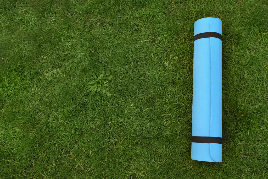 Bright karemat or fitness mat on fresh green grass outdoors, top view. Space for text - Photo, Image
