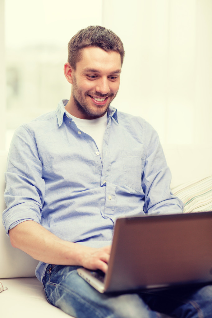 mosolygó ember dolgozik a laptop otthon - Fotó, kép