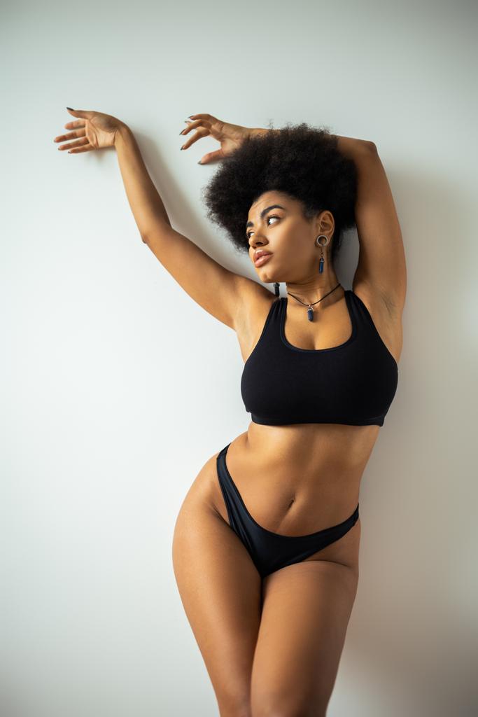 Sexy afrikanisch-amerikanische Frau in bauchfreiem Top und Höschen posiert in der Nähe der Wand  - Foto, Bild
