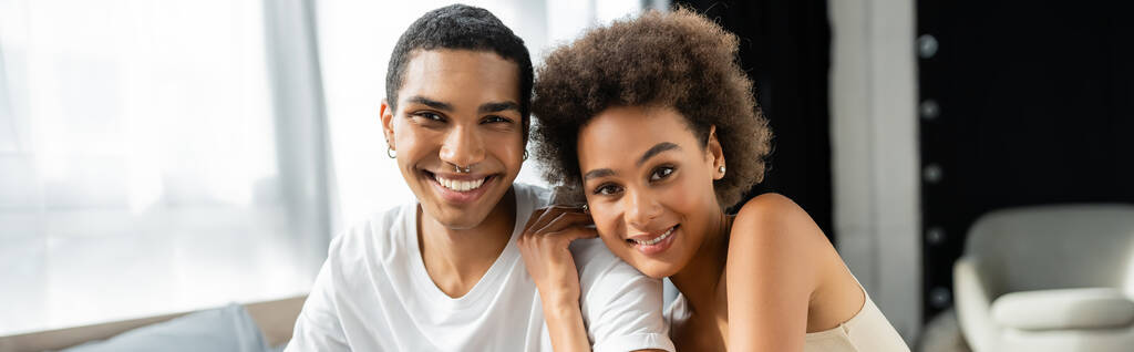 ブルネットアフリカ系アメリカ人女性抱擁幸せなボーイフレンドと笑顔でカメラ,バナー - 写真・画像