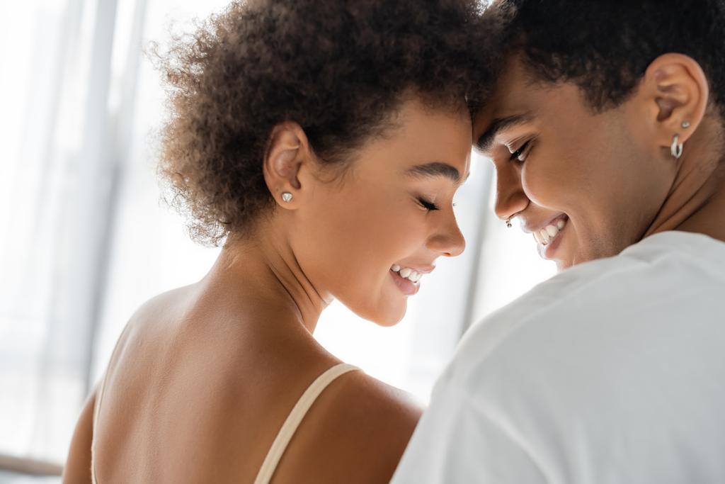 encaracolado afro-americano mulher e homem com piercing sorrindo com os olhos fechados  - Foto, Imagem