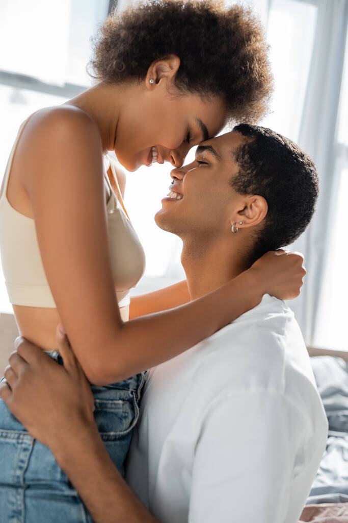 side view of african american couple hugging and smiling with closed eyes - Photo, Image