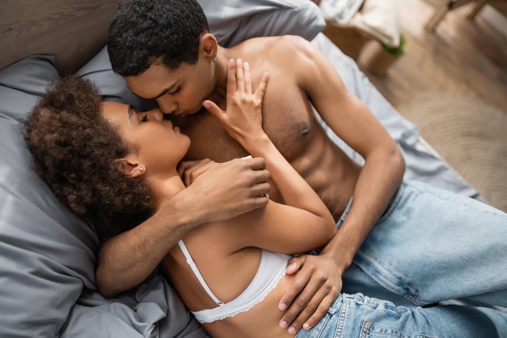ylhäältä näkymä seksikäs afrikkalainen amerikkalainen pari farkut syleilee ja suudella makuuhuoneessa - Valokuva, kuva