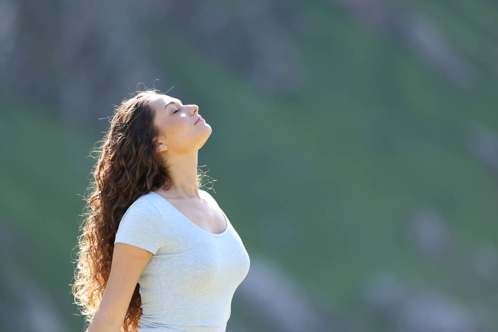 Vista lateral retrato de uma mulher respirando ar fresco na montanha um dia ensolarado - Foto, Imagem