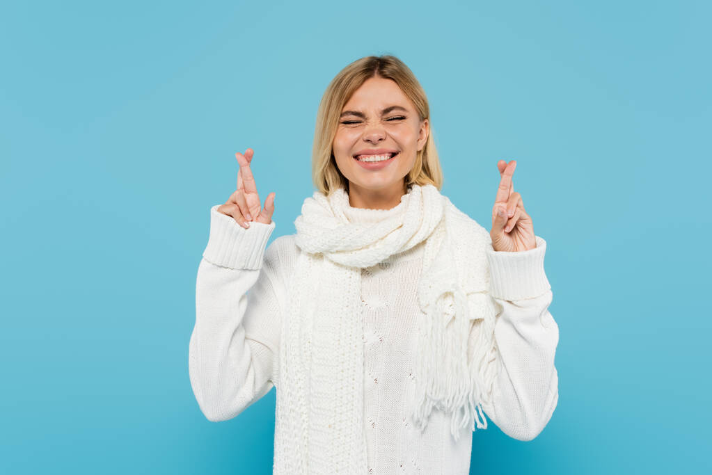 fröhliche blonde Frau in weißem Pullover und Schal, die vereinzelt die Daumen auf blau drückt - Foto, Bild