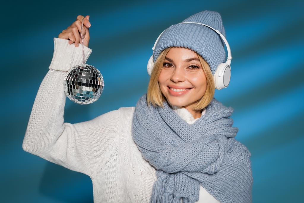 iloinen nainen talvella hattu ja langattomat kuulokkeet tilalla disco pallo sininen  - Valokuva, kuva