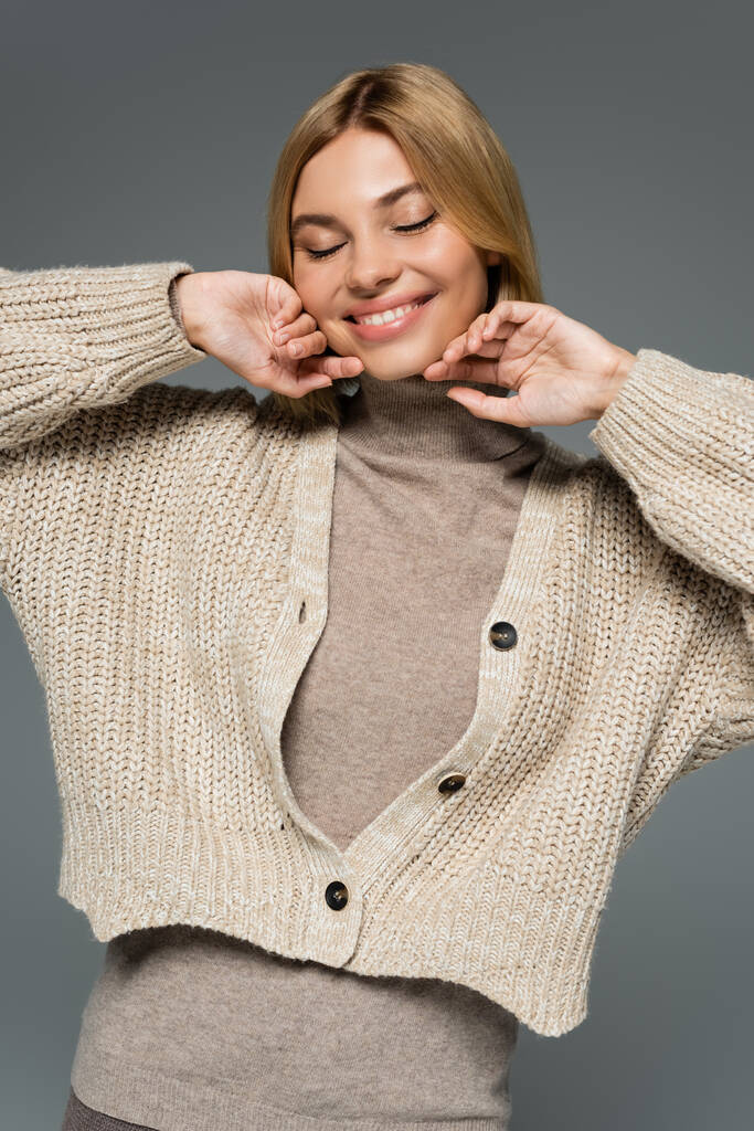 mulher loira alegre em gola alta e casaco de lã sorrindo com olhos fechados isolados em cinza - Foto, Imagem