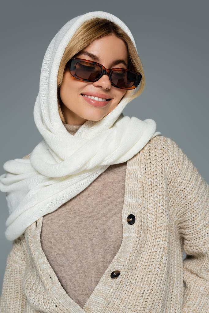 fröhliche Frau mit Kopftuch und stylischer Sonnenbrille, die vereinzelt auf grau lächelt - Foto, Bild