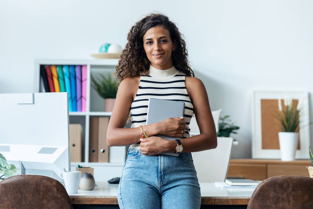 Shot van mooie zakenvrouw met behulp van haar digitale tablet terwijl zitten op een bureau in een modern startup kantoor. - Foto, afbeelding