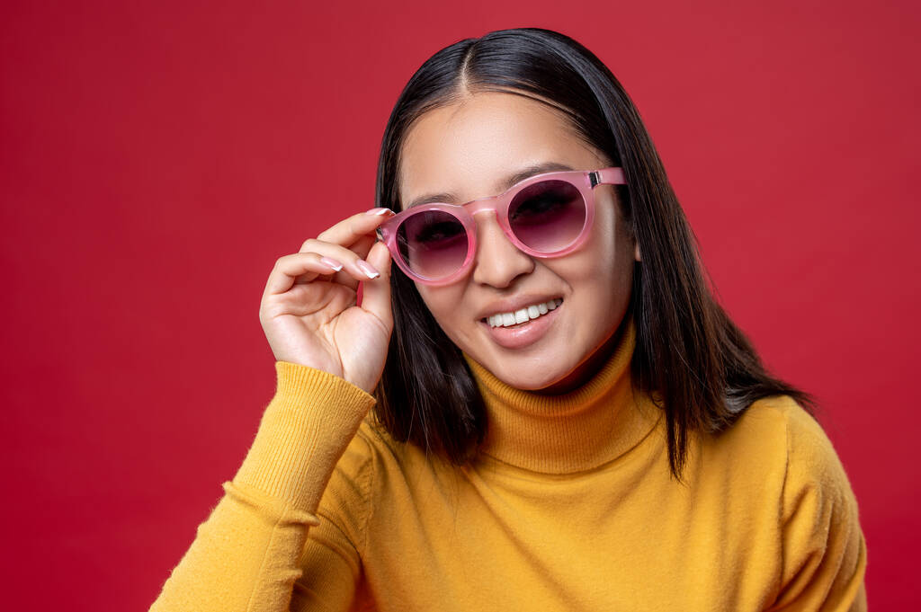 Portrét roztomilé radostné mladé asijské ženy ve stylových brýlích pózující pro fotoaparát - Fotografie, Obrázek