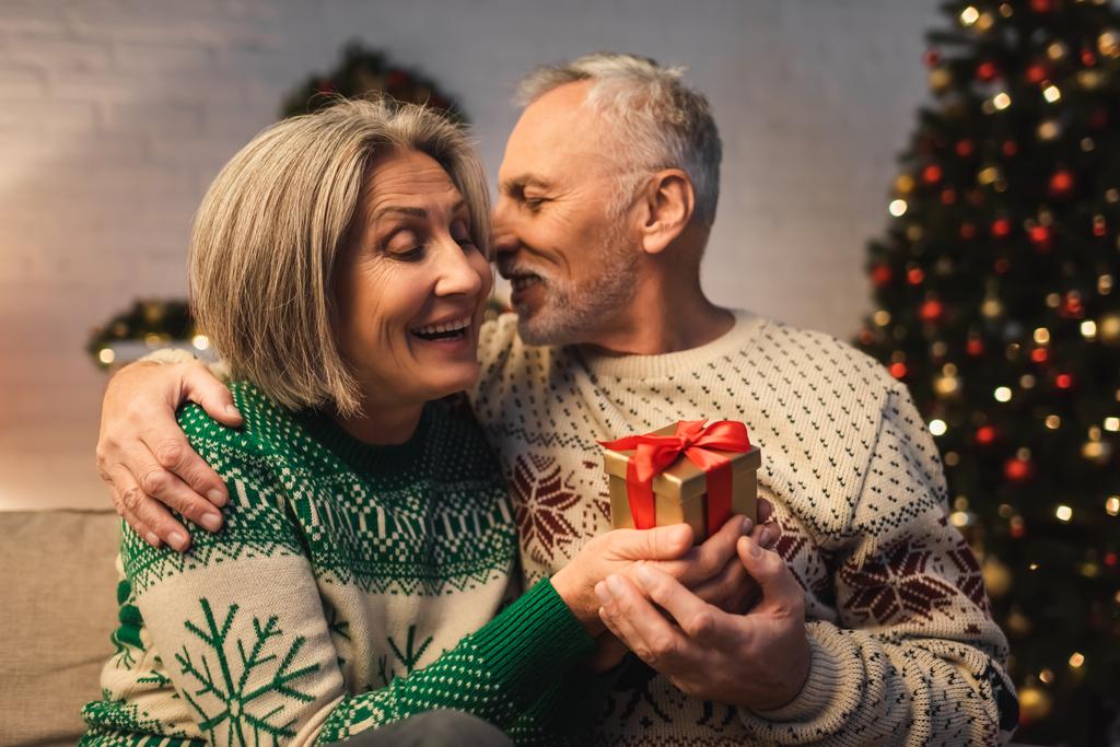 幸せな中年男でセーター巨大笑顔妻とともにクリスマスプレゼント - 写真・画像