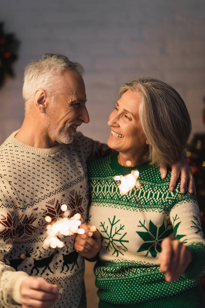 陽気な中年の男抱擁妻を持ちながらクリスマス前夜に輝く - 写真・画像